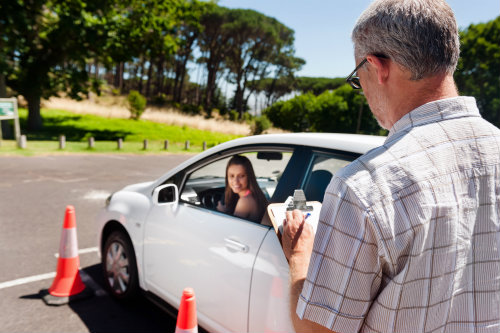 student driver in a car with an instructor taking notes