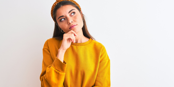 Girl in yellow sweater looking confused